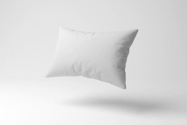 A pillow is floating in the air on top of a white surface.