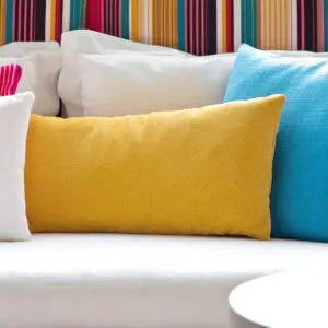 A white couch with several different colored pillows on it.