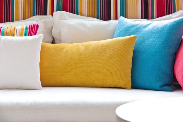 A white couch with several different colored pillows on it.